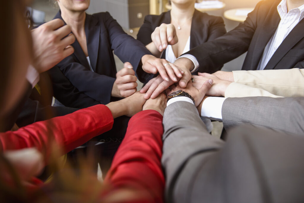 A group of colleagues join hands at the workplace symbolizing team building concept.